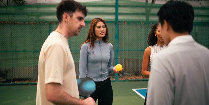 Multi ethnic group enjoying active discussion on a pickleball court