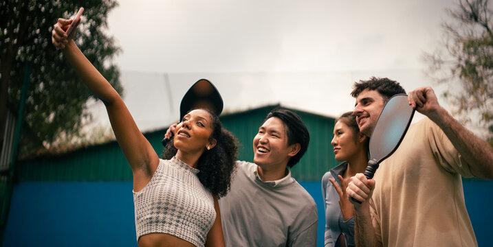 Diverse friends enjoying pickleball, taking a fun selfie on court