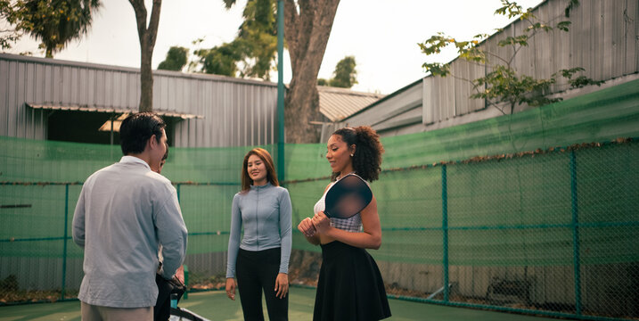 Diverse friends preparing for a pickleball game on an outdoor court