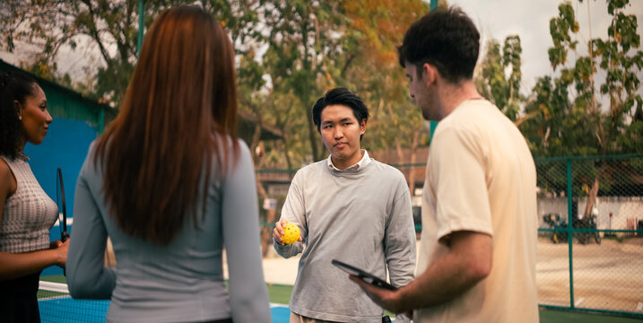 Group of diverse friends learning pickleball strategies on court