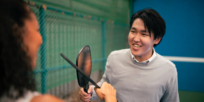 Pickleball players tapping paddles on court, celebrating a point