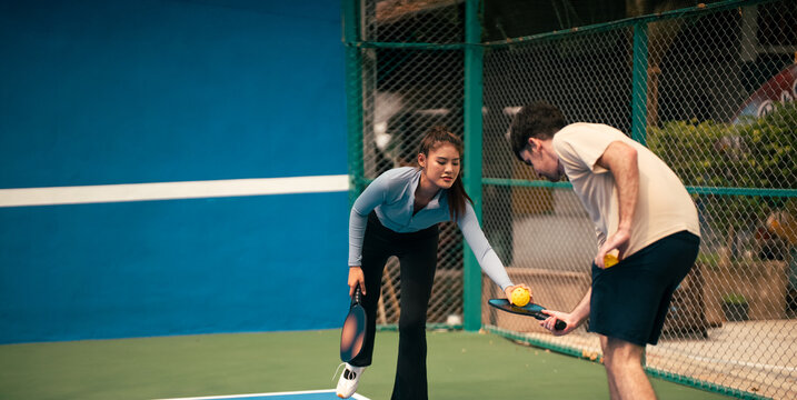 Teammates playing pickleball on court learning and helping each other