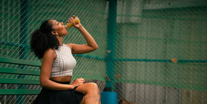 Young woman hydrating with fresh juice after a pickleball match