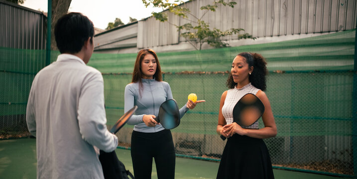 Diverse friends learning pickleball game listening to instructor