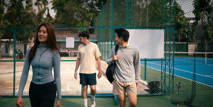 Young adults walking on sports court, friends arriving to play match