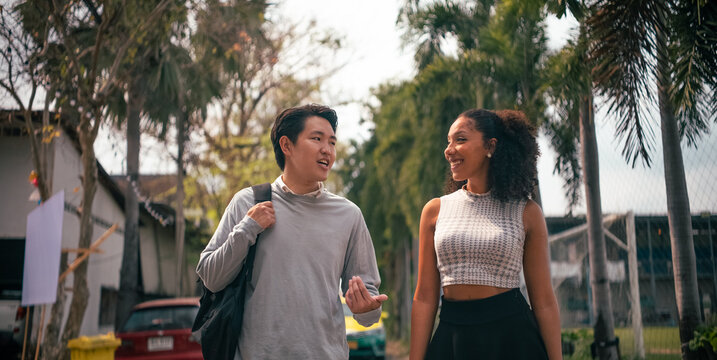 Young diverse friends talking and smiling while walking outdoors