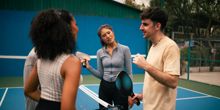 Diverse friends discussing strategy during a pickleball game on court