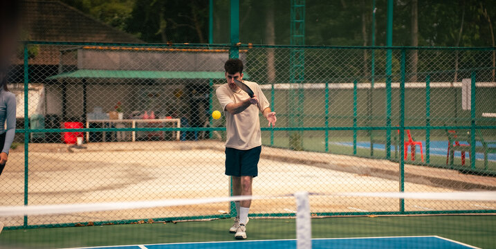Young man playing pickleball actively hits ball during intense game