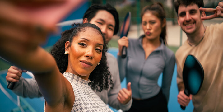 Diverse friends taking selfie on pickleball court after intense match