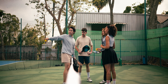 Group of friends learning pickleball on outdoor court in Bangkok