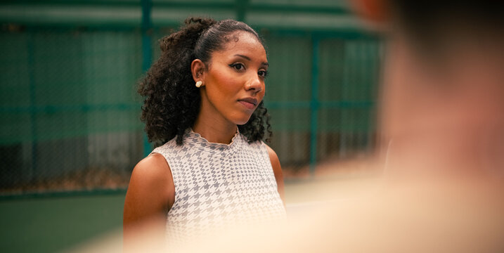 Young woman observing her friend on a pickleball court outdoors