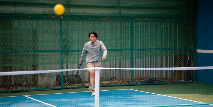 Focused athlete playing pickleball on outdoor court during a match