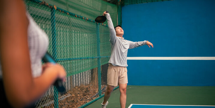 Man playing pickleball, serving ball during an intense game