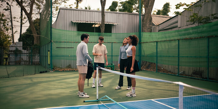 Young adults discussing pickleball rules on court before the match