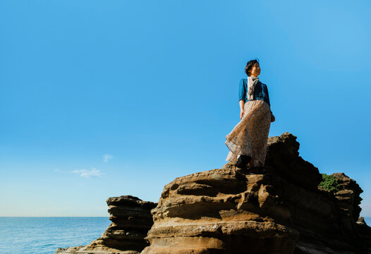 A Blissful Woman Basking in the Sea Breeze Under a Clear Blue Sky.