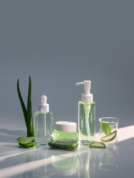 Aloe vera skincare products with fresh leaves on a reflective surface