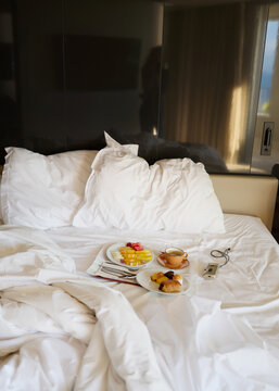 Breakfast Served in a Hotel Room With a Messy Bed and Soft Light