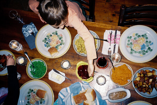 Overhead view of child reaching across dinner table on Thanksgiving