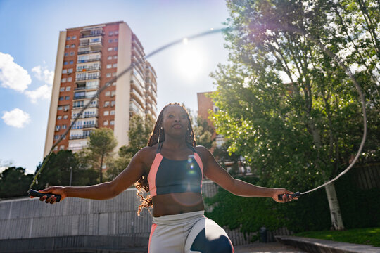 Woman jumping rope outdoors near tall building