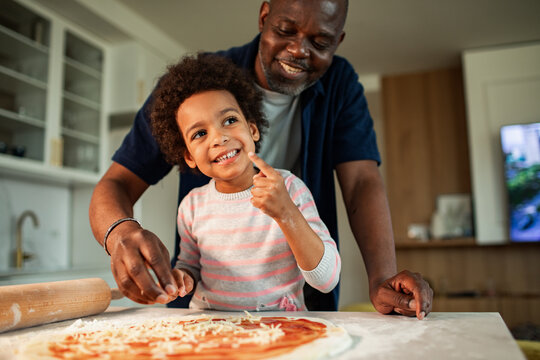 Father and daughter making homemade pizza in cozy kitchen