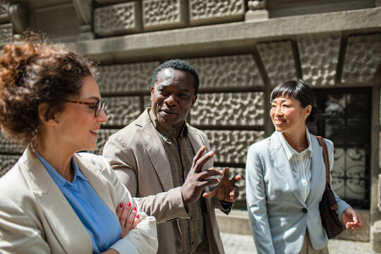 Three business colleagues talking while walking on a city street