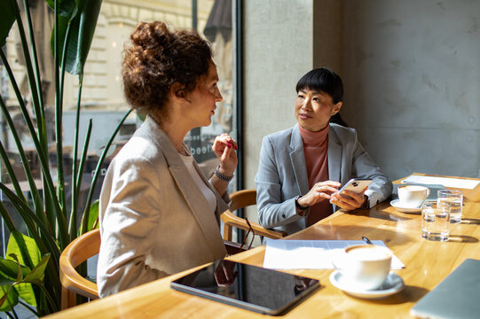 Two businesswomen discussing work over coffee in a cafe