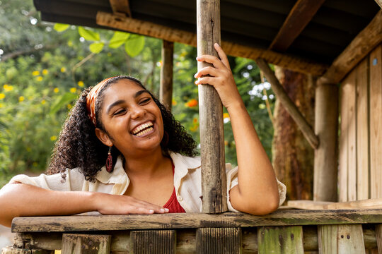 Joyful Woman Laughing Outdoors by a Rustic Cabin