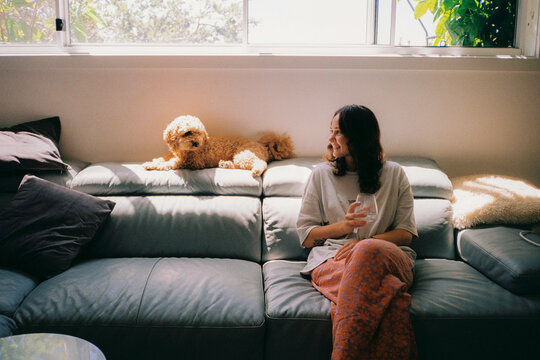 Woman drinks water and share the moment with dog at home 