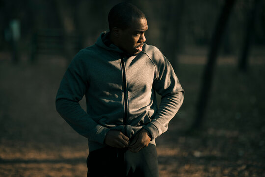 Athlete zipping hoodie in park at sunrise