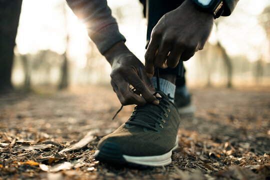 Runner tying shoelaces on forest trail at sunrise
