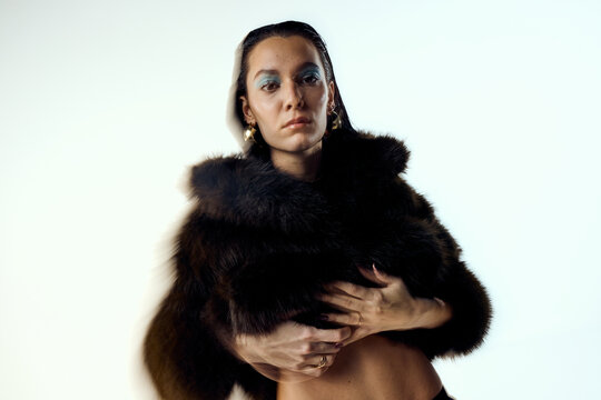 Handsome woman is wearing a fur coat in studio
