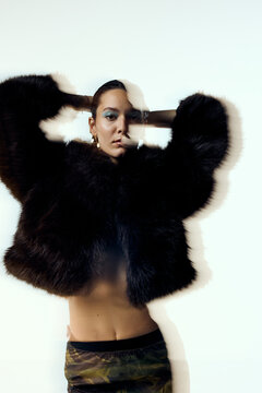 Beautiful woman is wearing a fur coat in studio
