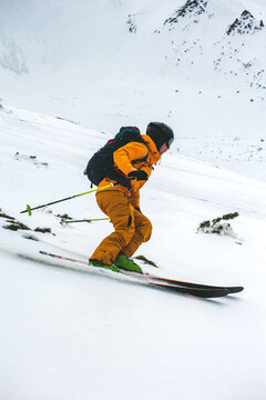 Man in an orange jacket makes the turn on skis