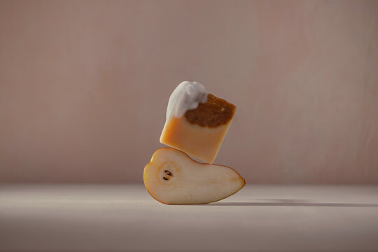 A bar of handmade soap is balanced on a fresh pear slice