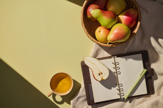 A serene still life with pears, notebook, pen, and a cup of tea.