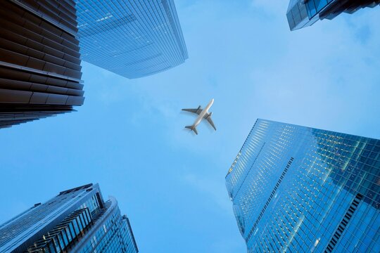 Airplane Flying Above Tall Buildings in a City Setting