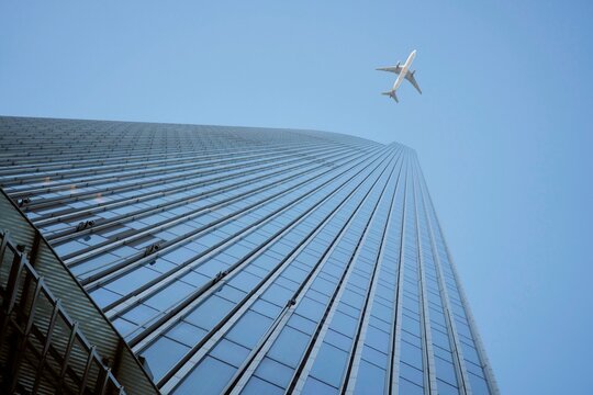 Airplane Flies Over Tall Building on a Clear Day