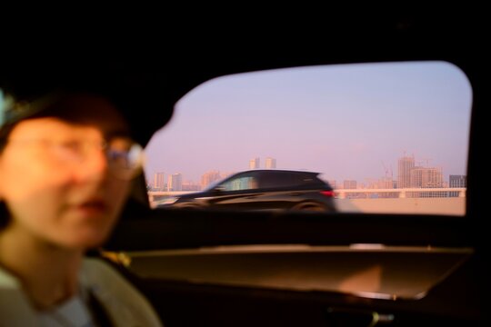 Person in electric Car Looking out at City Skyline During Sunset