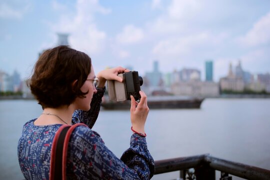Woman Takes Picture on the Waterfront in a City