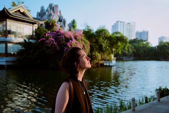 Woman Enjoys the View by the Lake in the City During Sunset