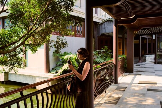Person Stands by Railing Near Water With Plants at a Location
