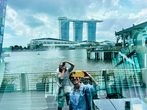 Two men taking selfie in glass reflection at Marina Bay Singapore