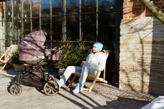 Man sitting in chair with baby stroller outside 