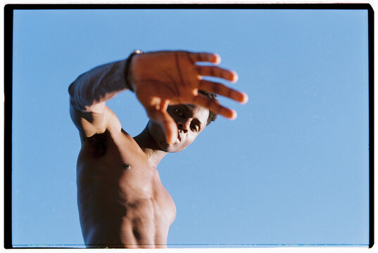 Man shielding eyes from bright sun against blue sky