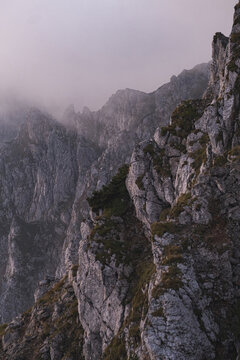 Dramatic Austrian cliff rising through misty mountain air at sunset.
