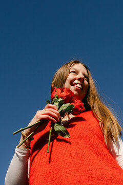 happy young woman with red top holding red roses 