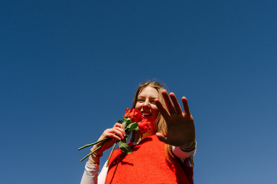 happy young woman with red top holding red roses 