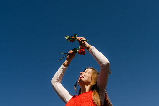 happy young woman with red top holding red roses 