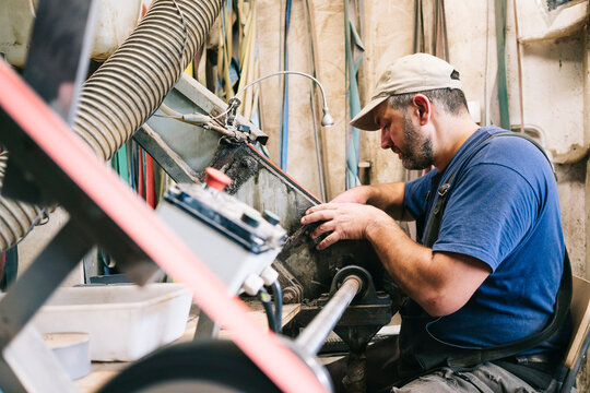 Craftsman grinding knife blade in metalworking workshop