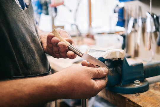 Craftsman holding handmade folding knife in workshop